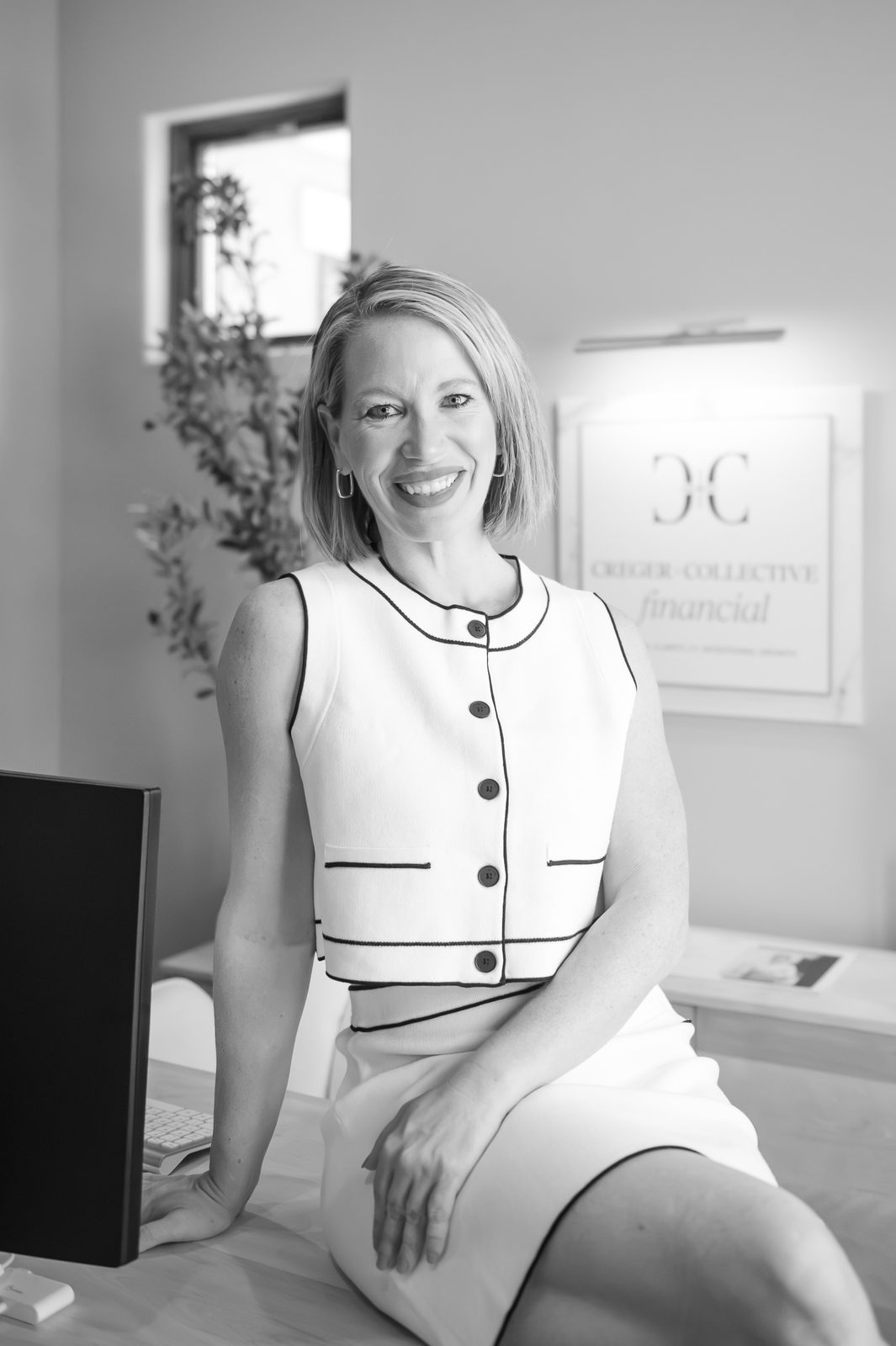 Angelina Creger, founder and CEO of Creger + Collective Financial, smiling in a black and white portrait in her office