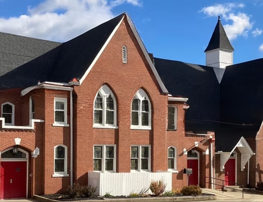 The red brick exterior of Mt. Olive Baptist Church in Canonsburg, Pennsylvania, with its white steeple and red doors
