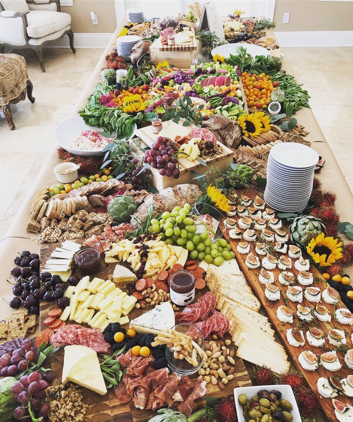 A long grazing table of cheeses, charcuterie, grapes, crostini and sunflowers