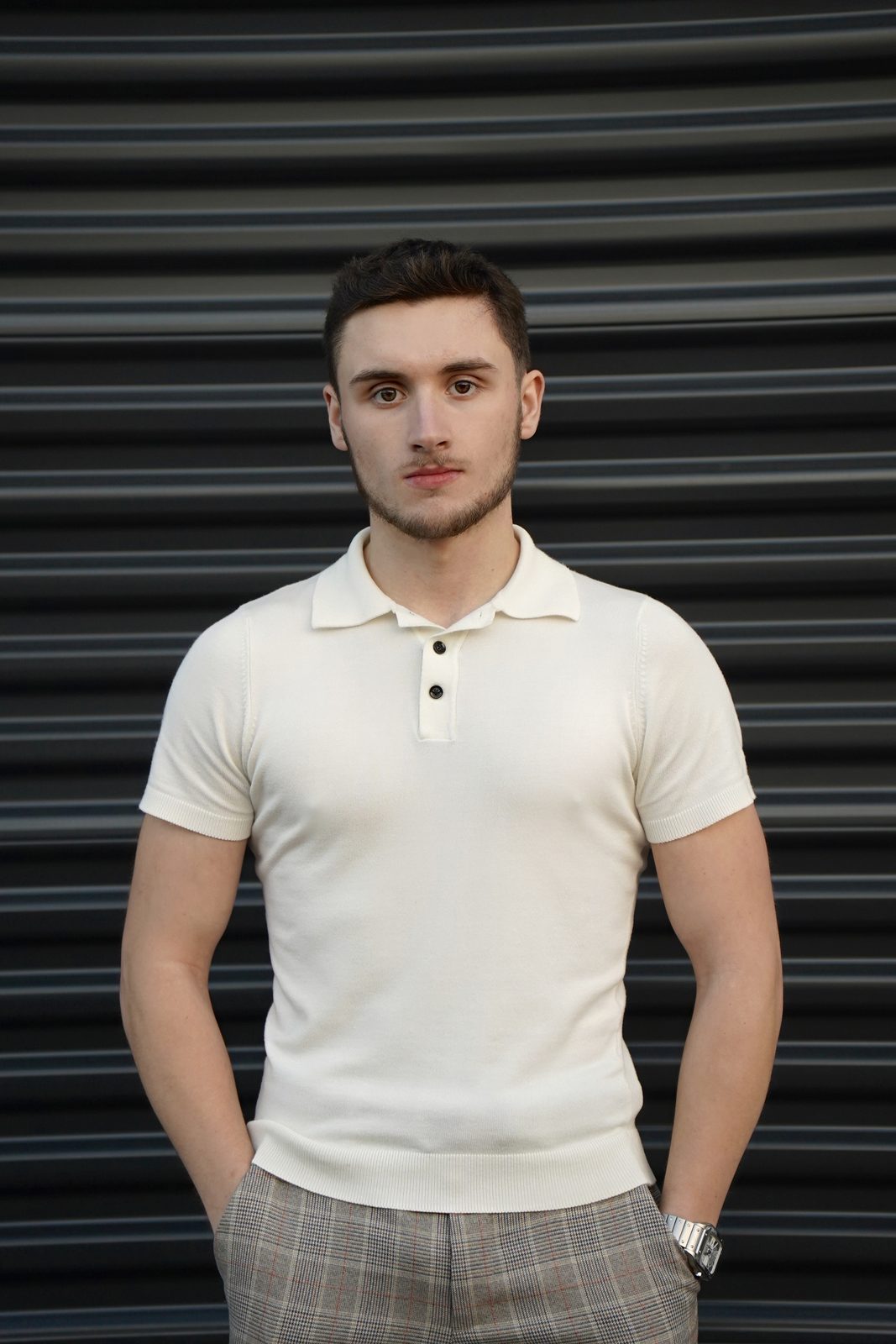 Austin Coburn, founder of Klicc MultiMedia, standing in a cream knit polo in front of a black roller shutter in Chicago
