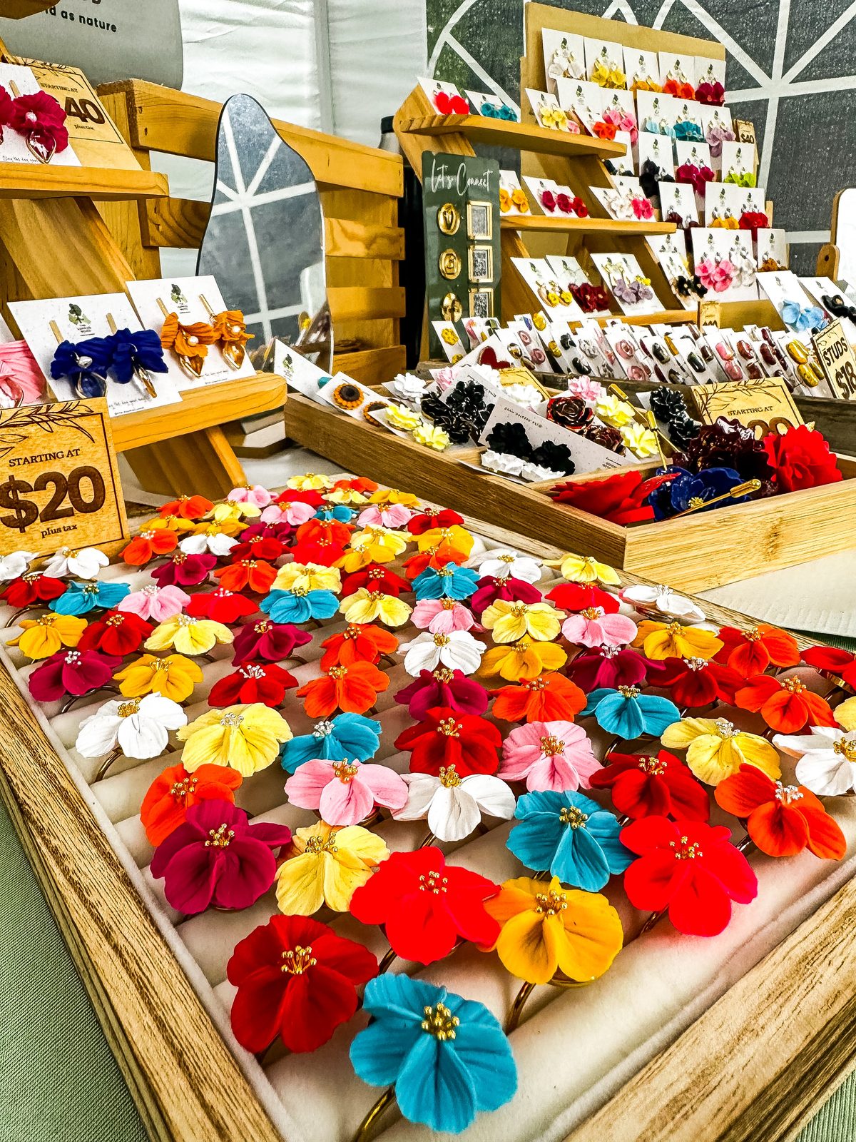 The Dappled Wood market booth with trays of colorful flower earrings and wooden display stands