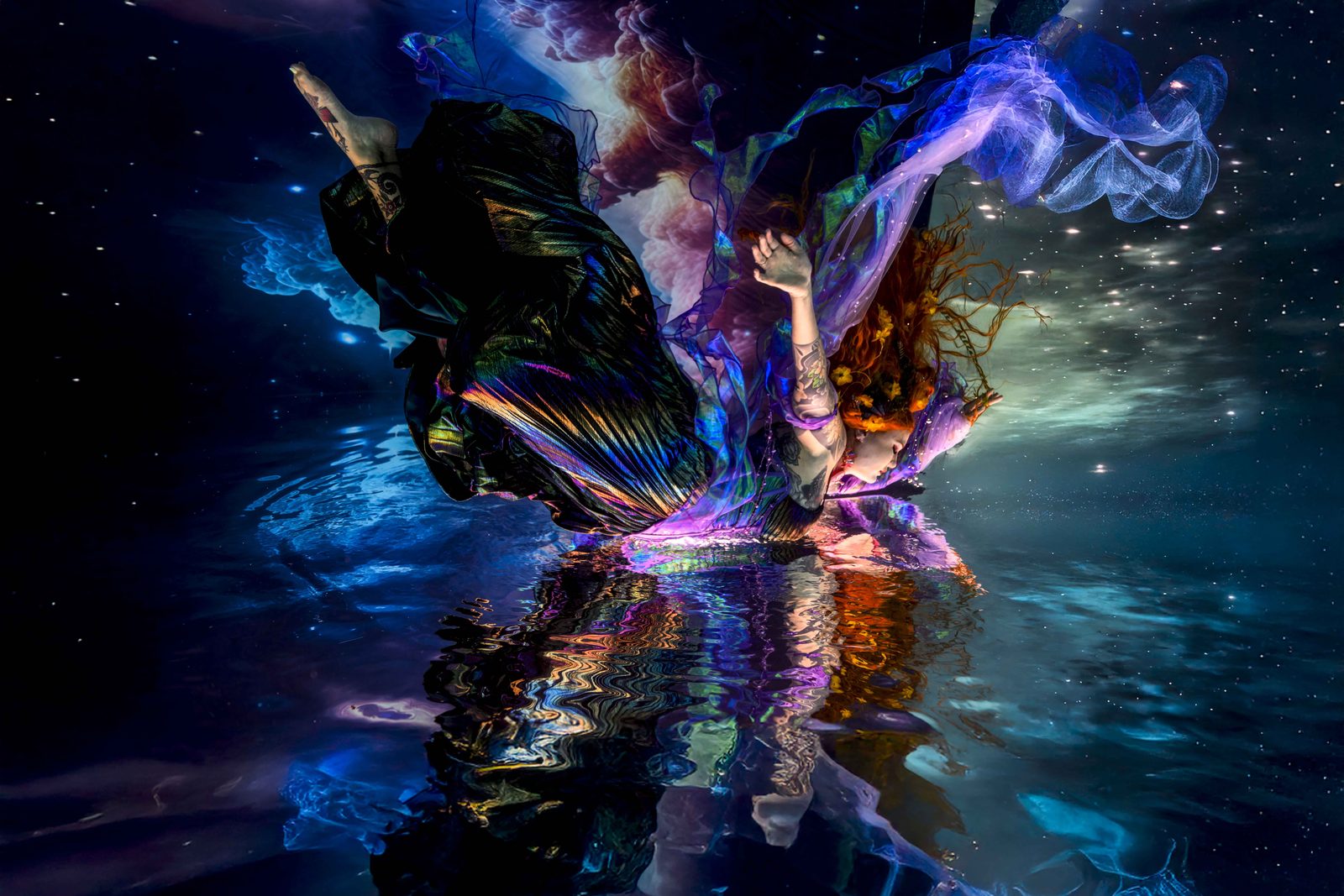 Angel Flying, a fine art underwater portrait by Bruce Campbell of a model in flowing iridescent fabric against a starry backdrop