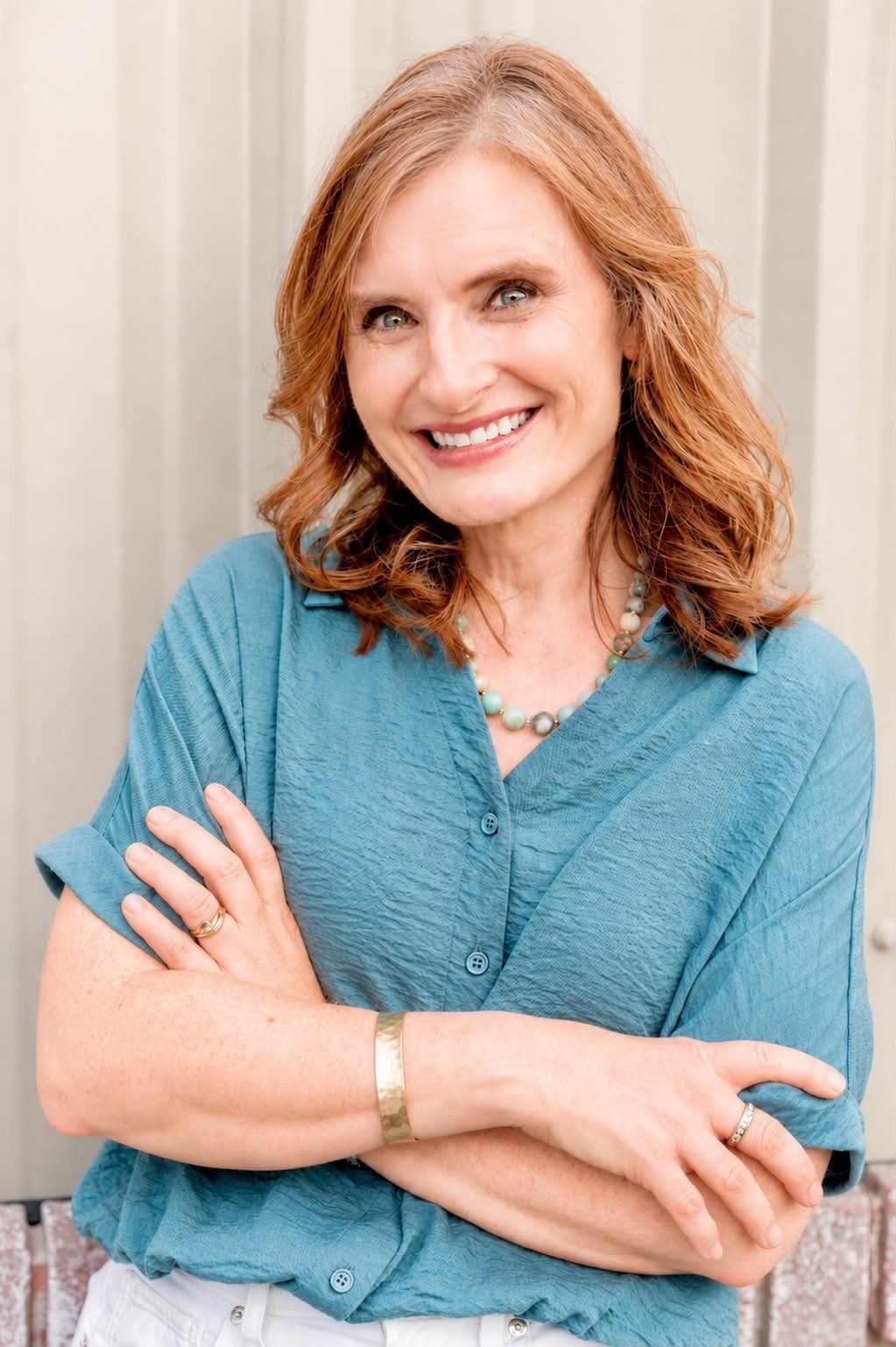 Elizabeth Geiger Harvey, founder of Renewal Therapeutics, smiling with her arms crossed in a teal blouse