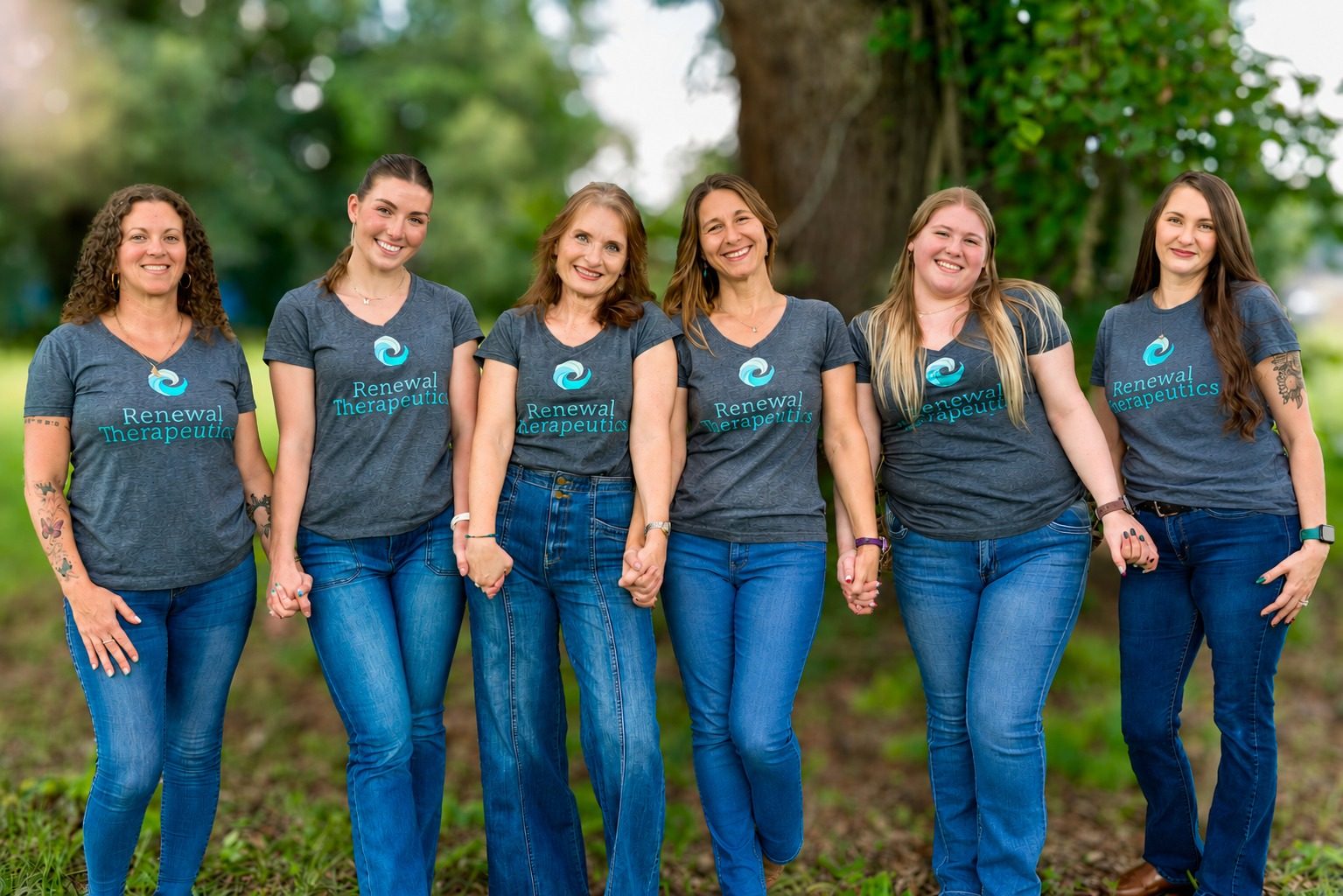 Elizabeth Geiger Harvey and five members of her team holding hands outdoors in matching Renewal Therapeutics T-shirts