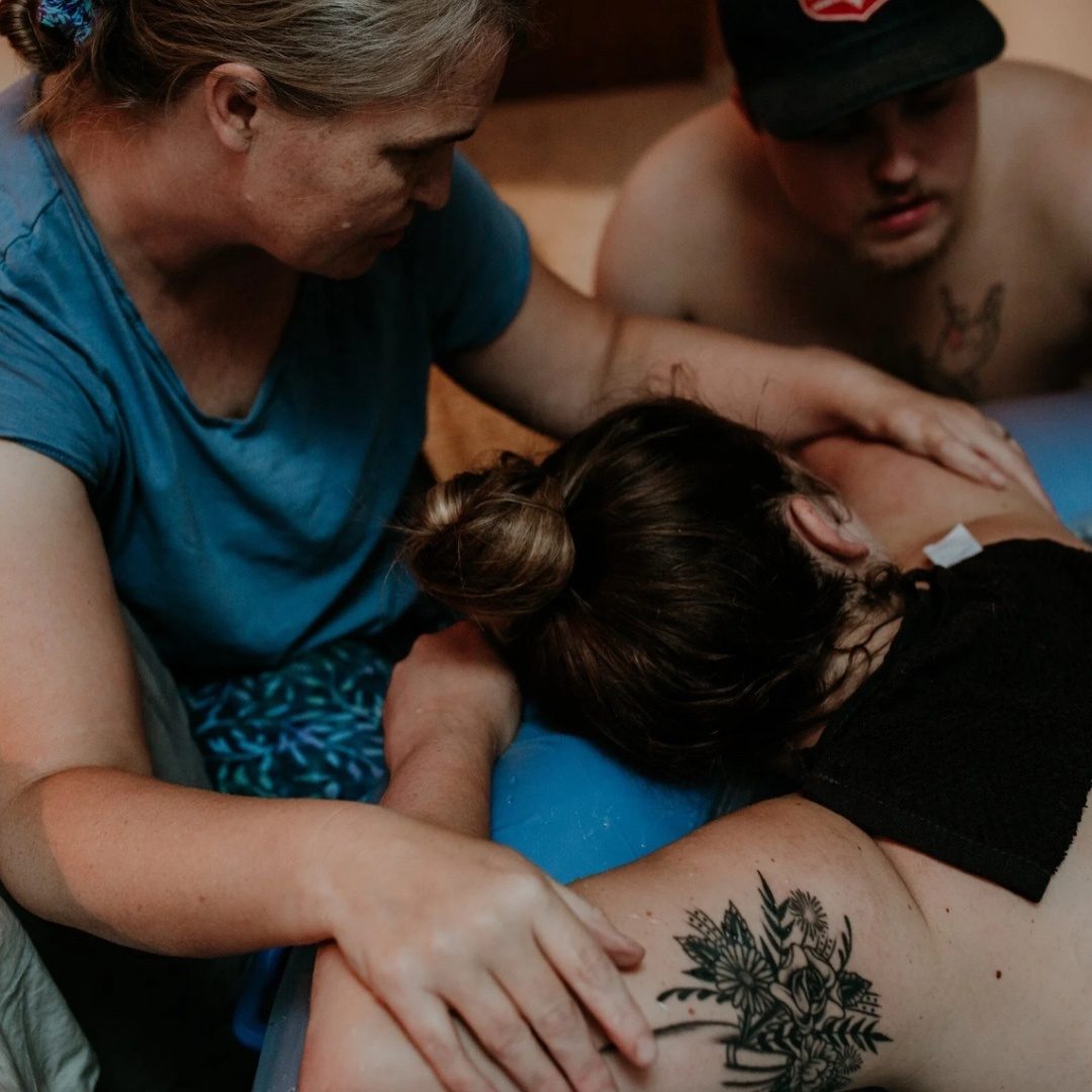 Gabrielle Lazarus providing hands-on doula support to a laboring client alongside her partner
