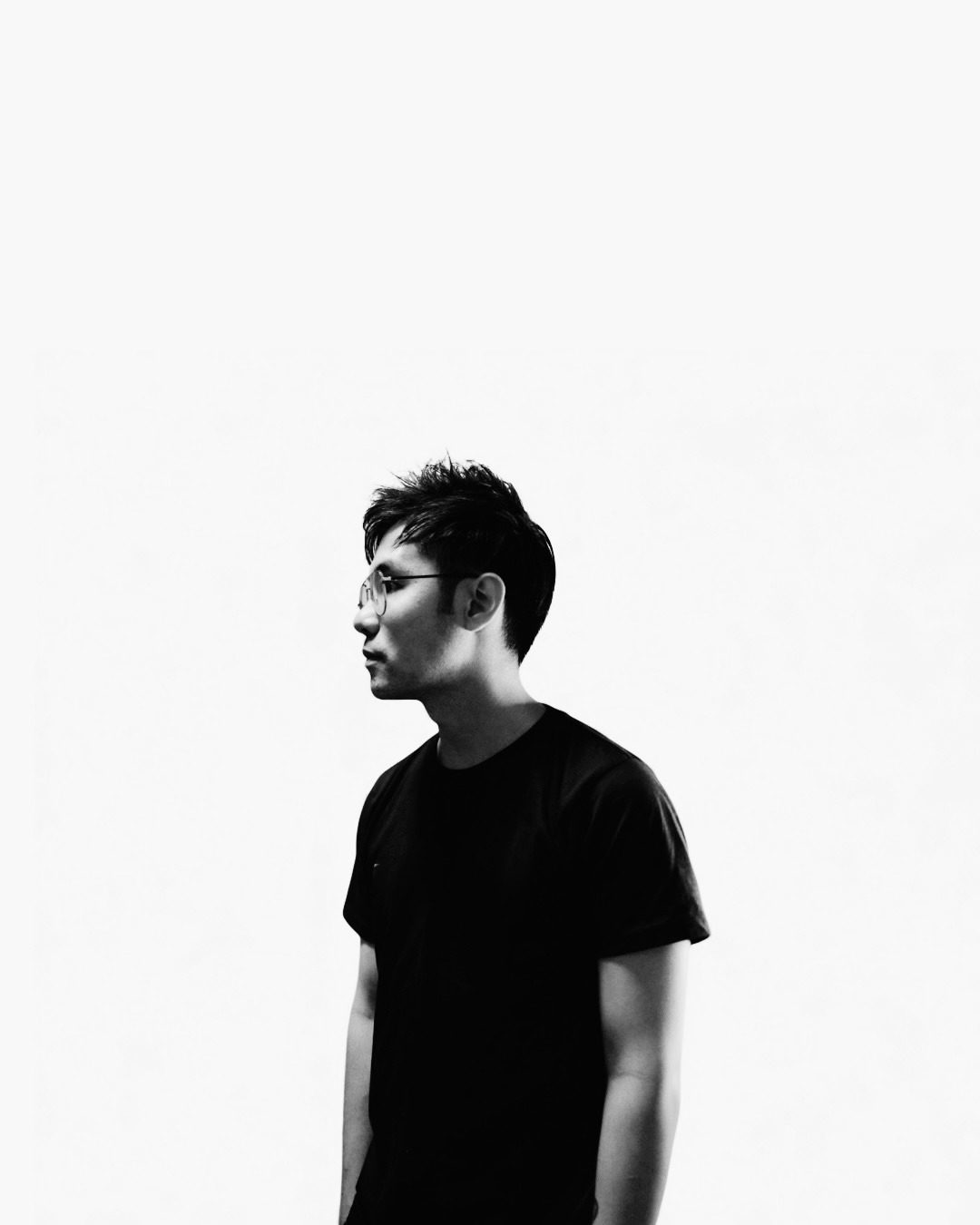Black and white studio portrait of Gregory Tan in profile, wearing a black T-shirt against a white backdrop