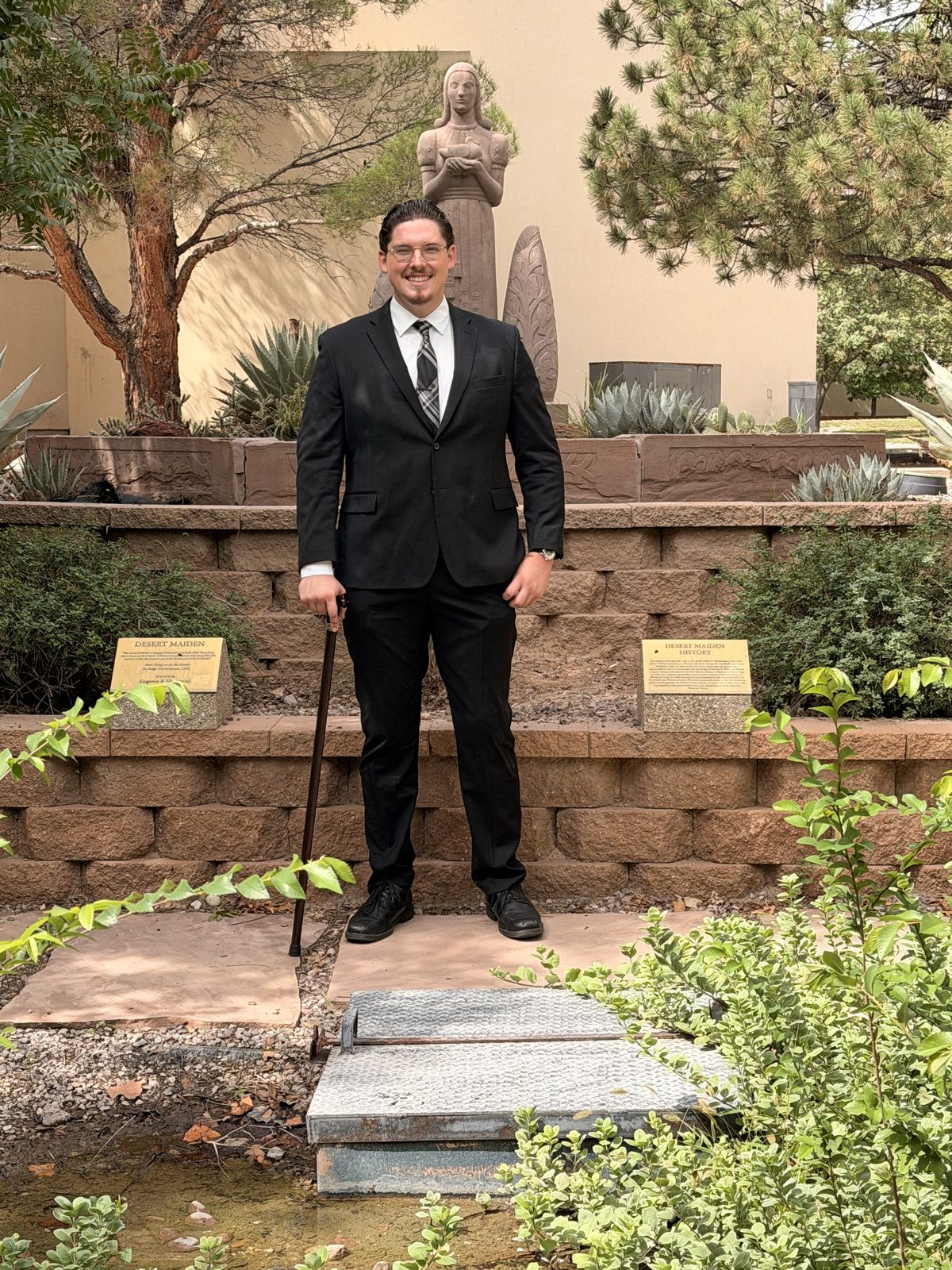 Jacob Sneed standing in a suit in a desert garden in Socorro, New Mexico