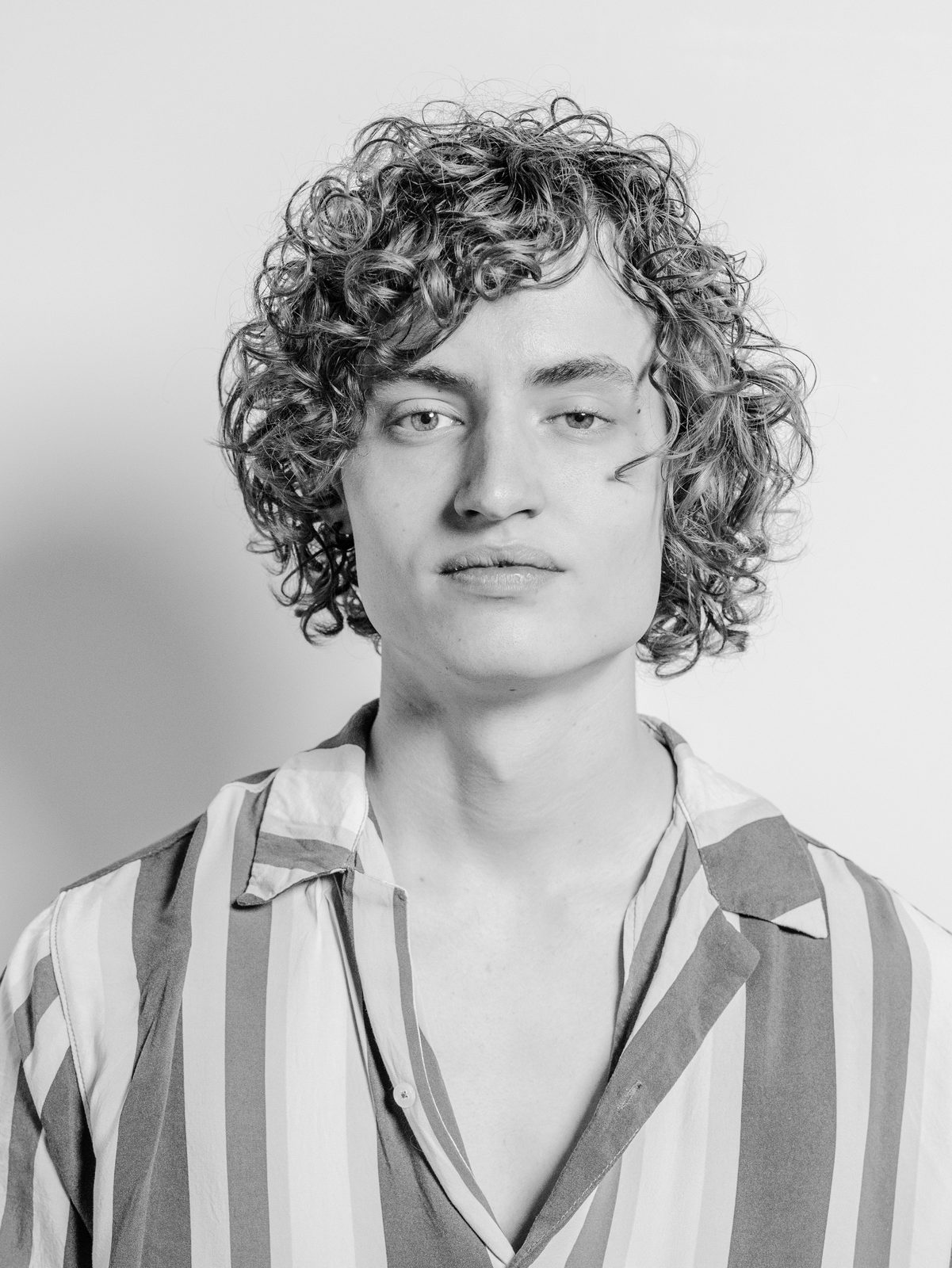 Josh Luke, owner of Josh Luke Music and Audio LLC, in a black and white studio portrait wearing a striped shirt