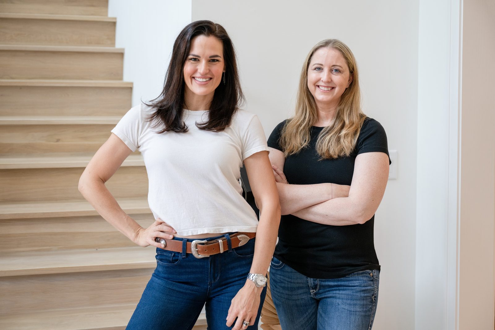 Kathryn Currey standing by a staircase with a colleague from the Friday team, both smiling