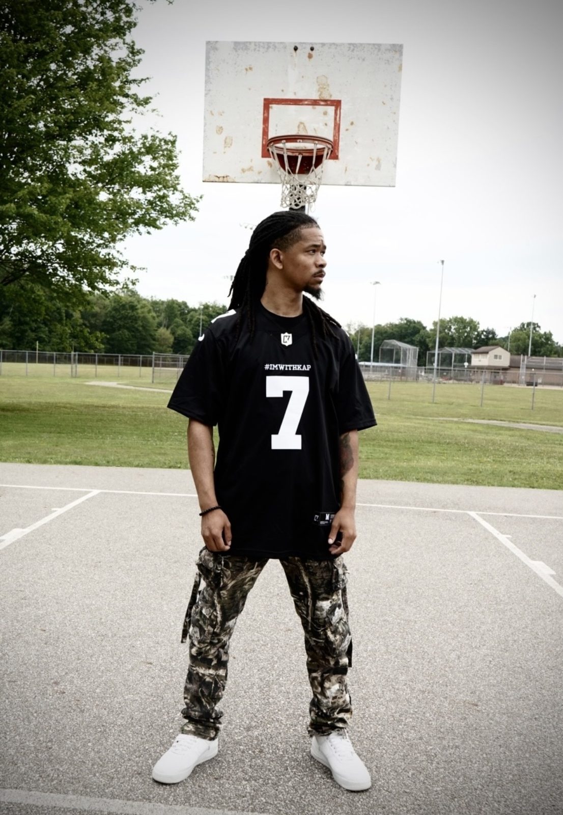 Khalid Thornton, the Cleveland artist and producer known as KTGODUMB!, standing on an outdoor basketball court in a number 7 jersey