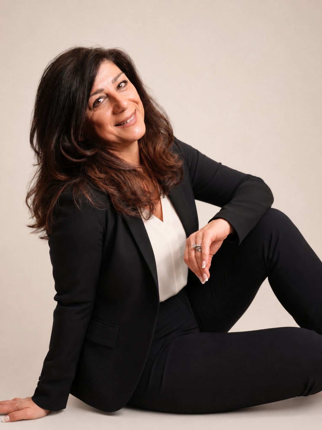 Kobi Julian, founder of Kobi Julian Inc., seated in a black suit in a studio portrait