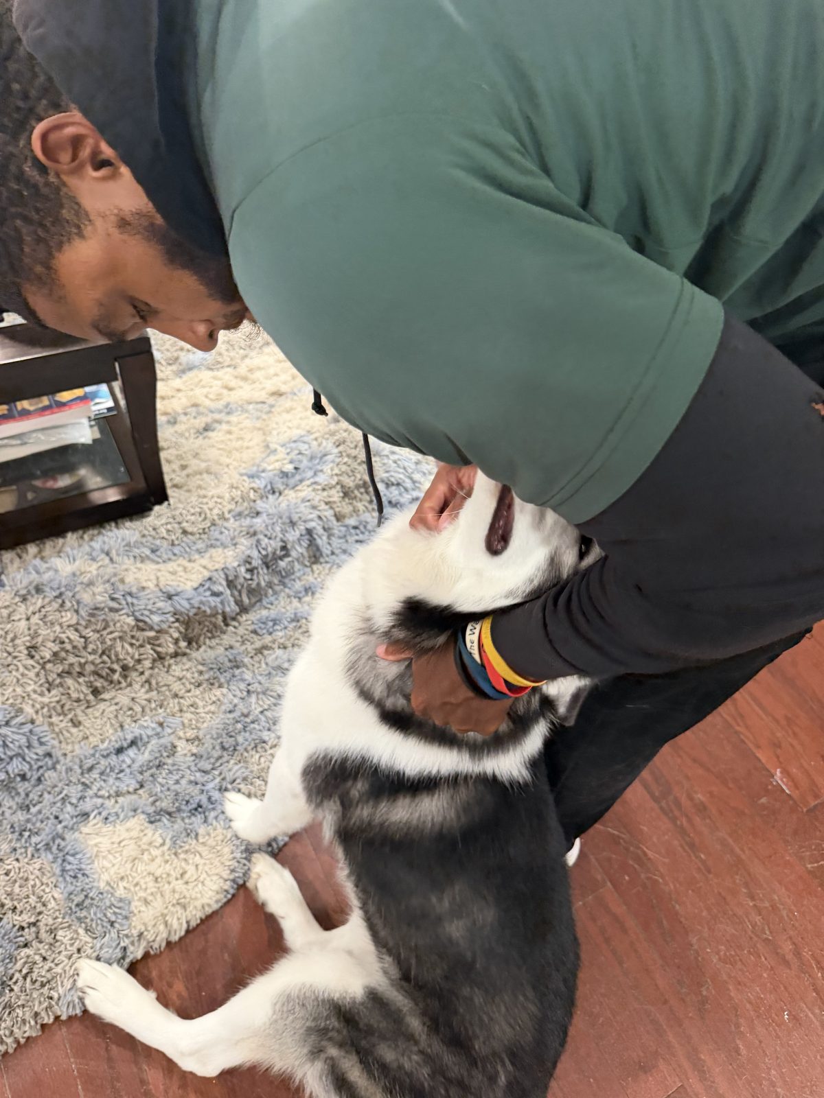 Lance Felder bending down to greet a husky on a living-room rug