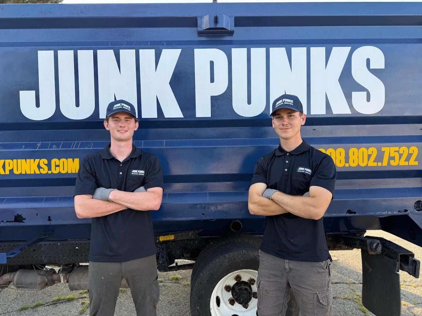 Logan Sullivan and co-founder Ryder Radke standing with arms crossed in front of a Junk Punks truck