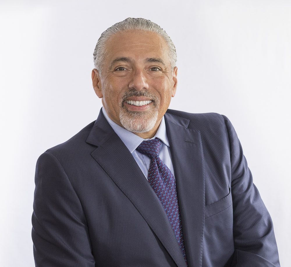 Marcus Hernandez, president of Hernandez Accounting Solutions, smiling in a navy suit and purple tie