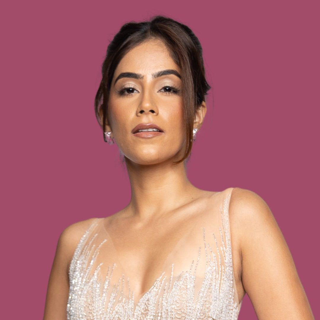 Nikita Tanwani, founder of CONQUER, in a beaded ivory gown against a deep rose backdrop