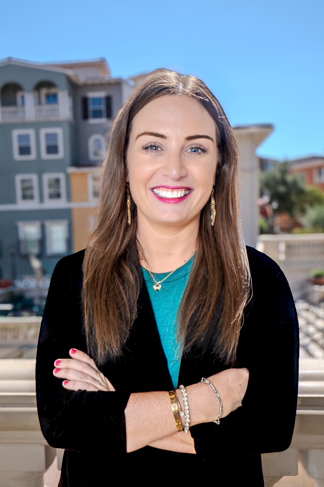 Rebecca Beebe, founder of Yellow Rose Counseling, smiling with arms crossed in a black blazer and teal top on a sunny balcony