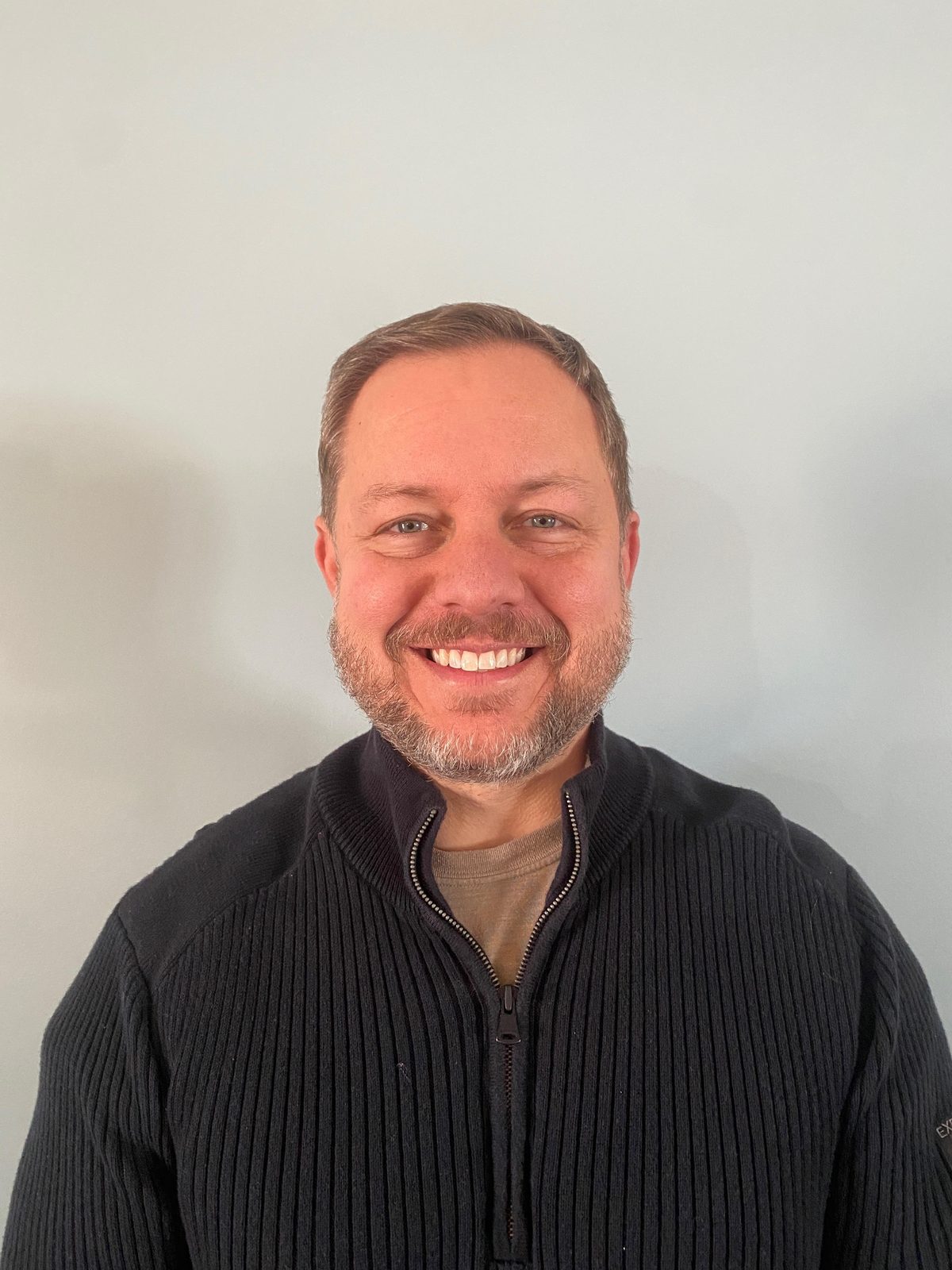 Richard Sias, owner of WeCare Solutions, smiling in a black zip sweater