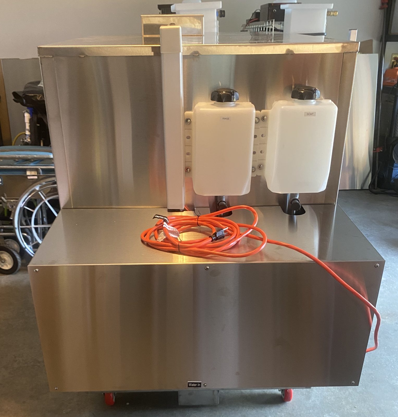 A WeCare Solutions stainless steel wash cabinet with chemical reservoirs on top