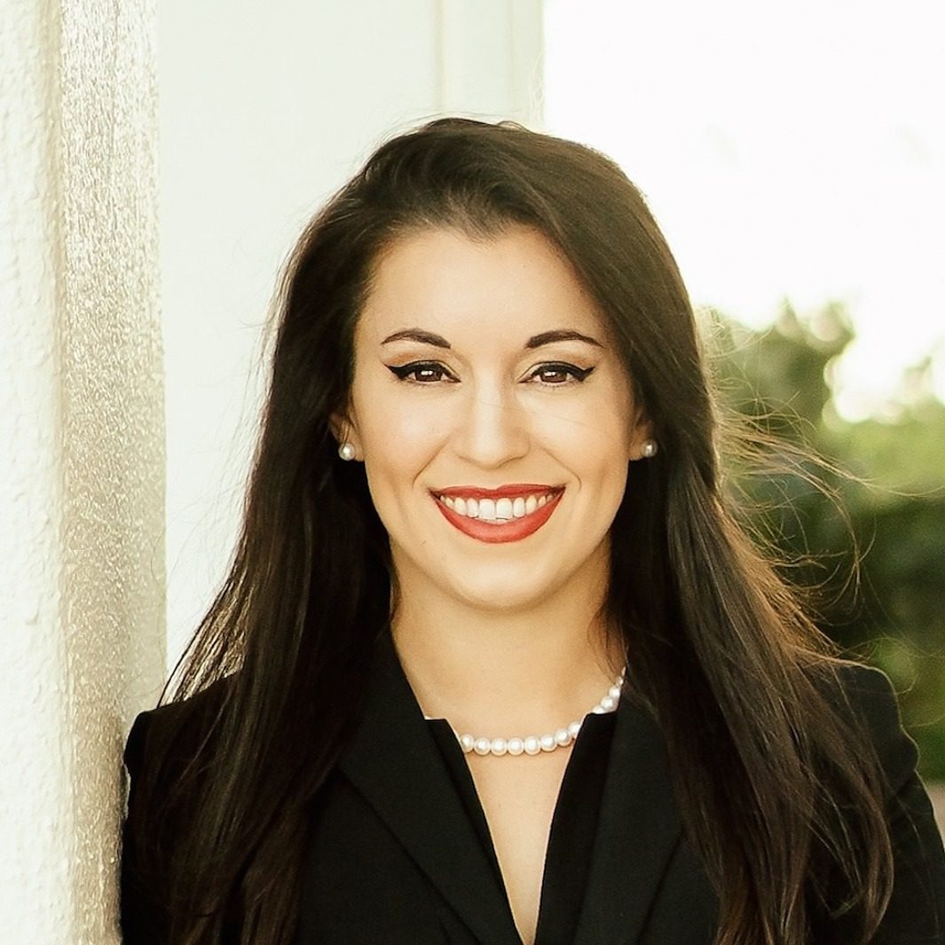 Sara Varnado, founder of A New World Immigration Law, smiling in a black blazer and pearl necklace