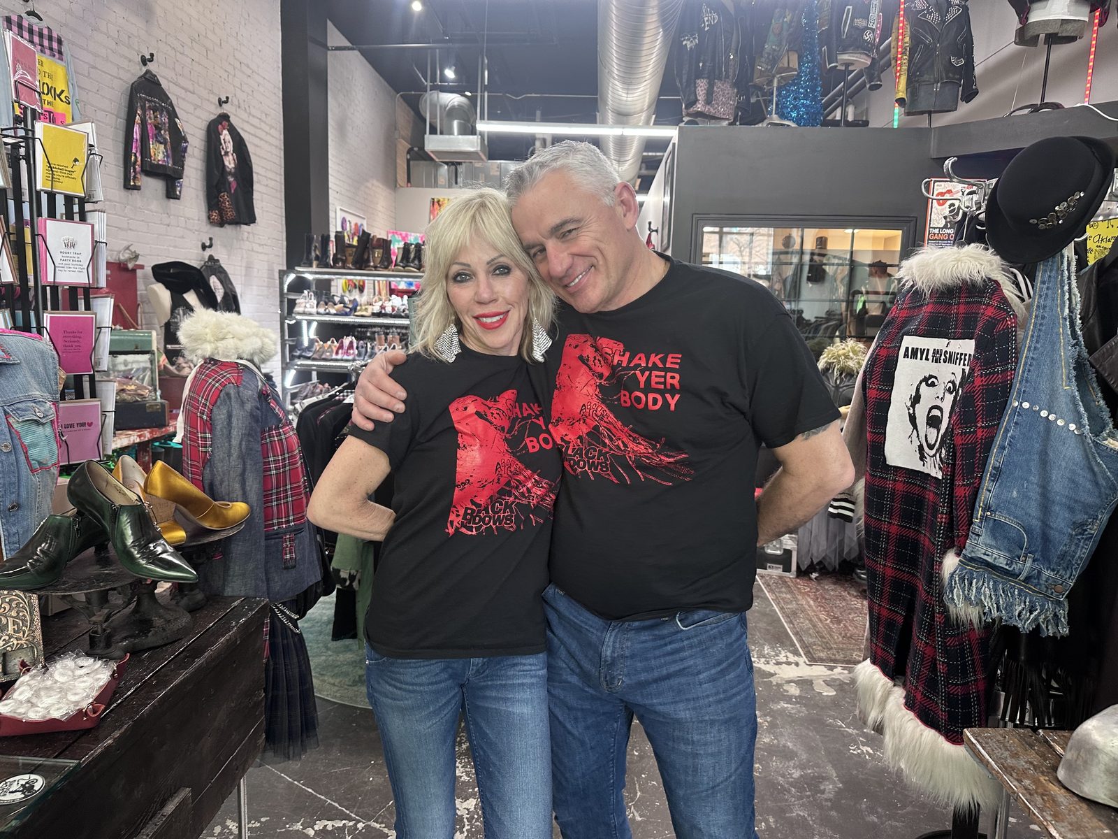 Staci and Eric Caillé in matching graphic tees inside the Reckless Swagger shop