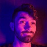 AJ Finnegan, the illustrator, animator and designer behind Finnegan Studio, in a portrait lit in violet and blue