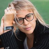 Anna Kumantsova, founder of Kumantsova Productions, in glasses and a pinstripe jacket with windblown hair
