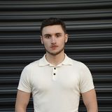 Austin Coburn, founder of Klicc MultiMedia, standing in a cream knit polo in front of a black roller shutter in Chicago