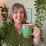Bridget Willard, founder of Bridget Willard, LLC, smiling in a green polka-dot blouse and holding a Corpus Christi sea turtle mug