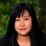 Hailey Herrera, watercolor batik artist in College Station, Texas, in a black top against a soft green woodland background