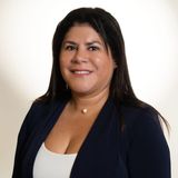 Hilda Rodriguez, founder of Dahil Bar in Miami, in a navy blazer and pearl necklace against a cream backdrop