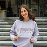 Kristen Sellars, the occupational therapist behind OT Insider, smiling in an Occupational Therapy sweatshirt on a flight of stone steps