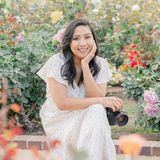 Sarom Thompson, San Diego family photographer, smiling in a rose garden with her camera