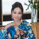 Shiho Brenner, author, kimono ambassador and founder of Kimono Suishin in San Diego, seated in a blue floral kimono with a crystal necklace and earrings